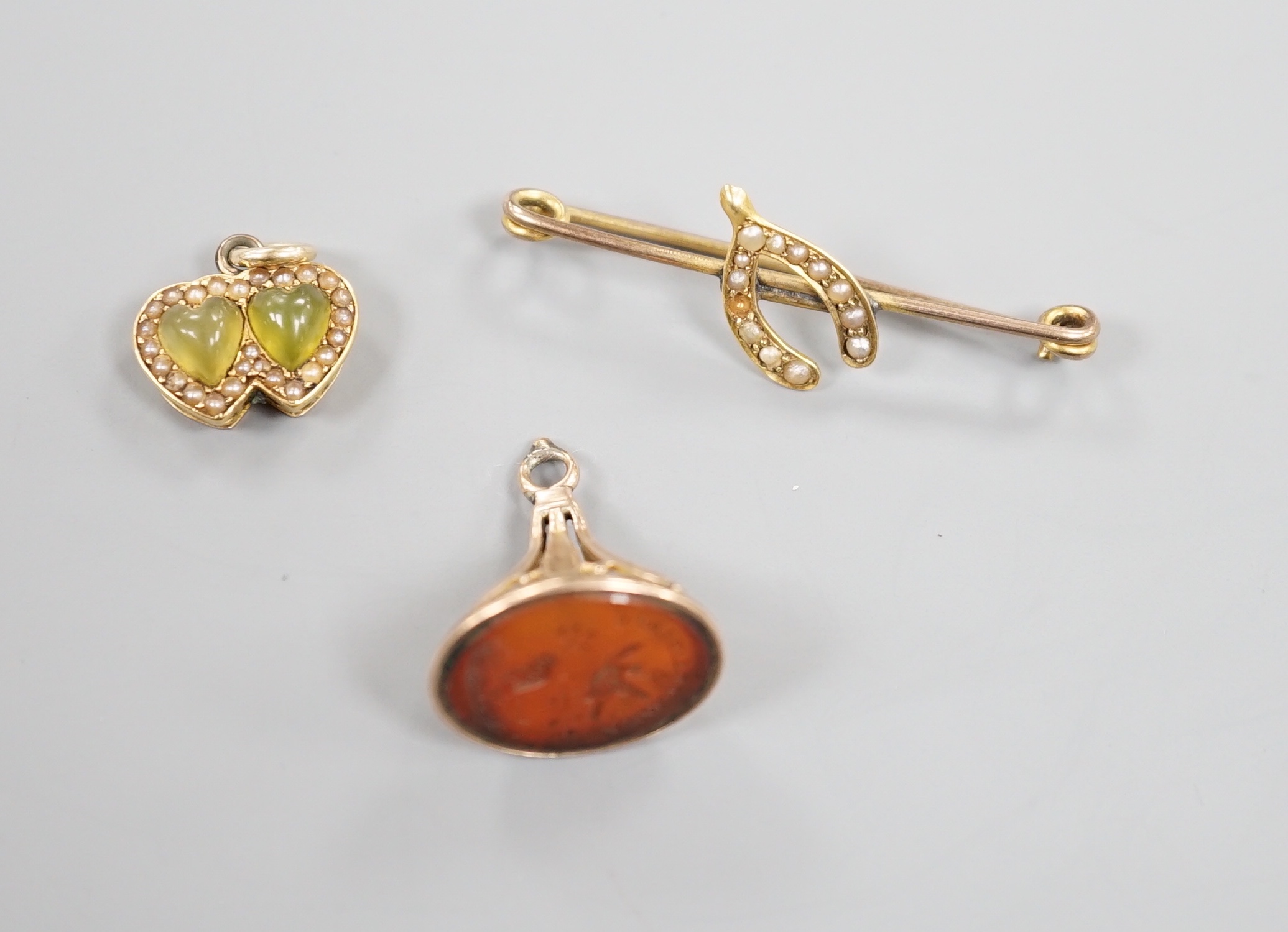 A yellow metal olivine? and seed pearl set twin heart pendant, width 15mm, a 19th century carnelian set fob seal and a wishbone bar brooch.